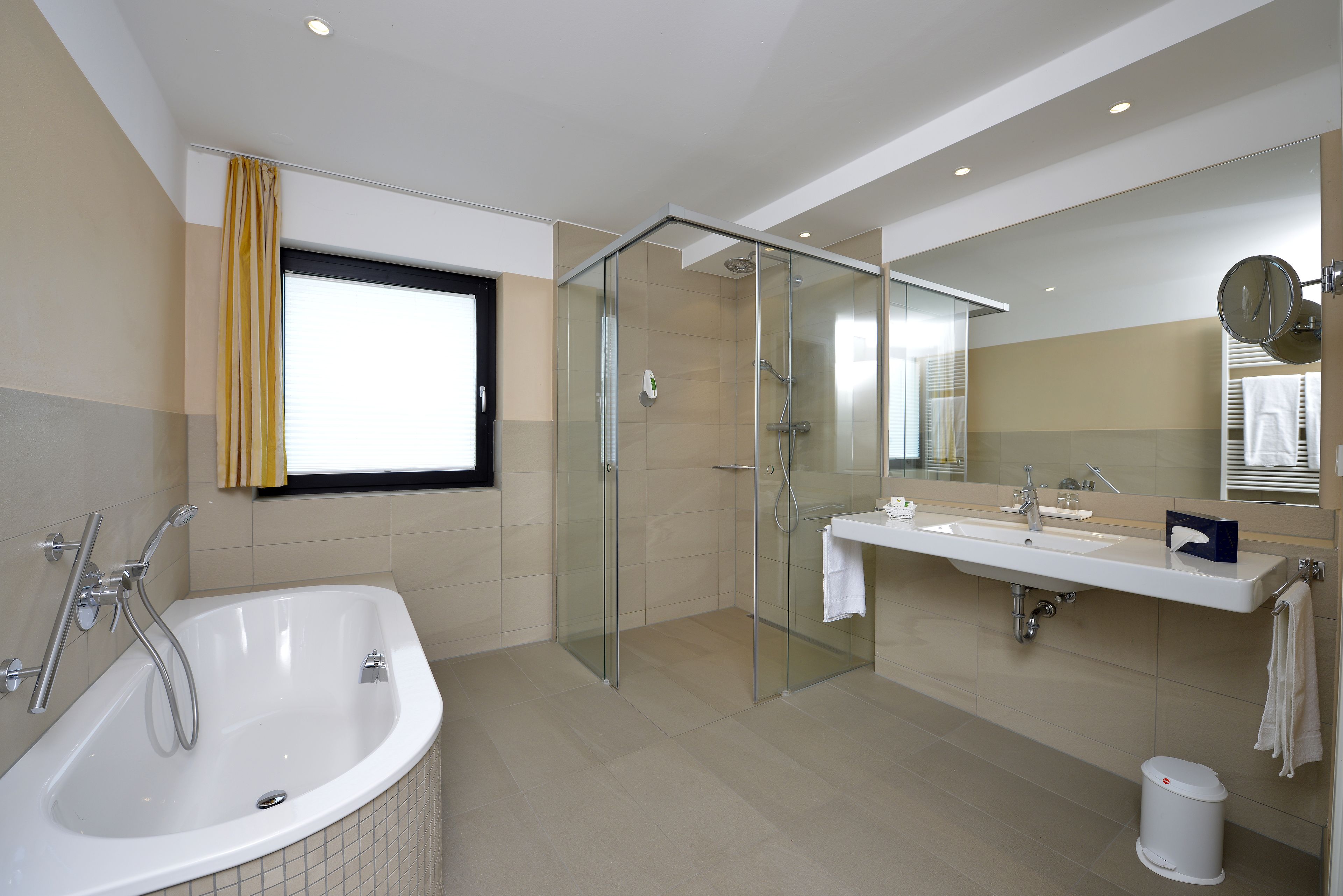 Un baño moderno con cabina de ducha de vidrio, bañera independiente y tocador con espejo.