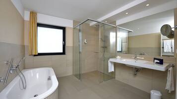Un baño moderno con cabina de ducha de vidrio, bañera independiente y tocador con espejo.