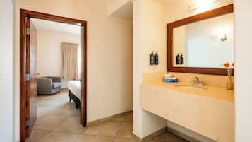 A hotel bathroom with a large mirror, a sink, and toiletries.