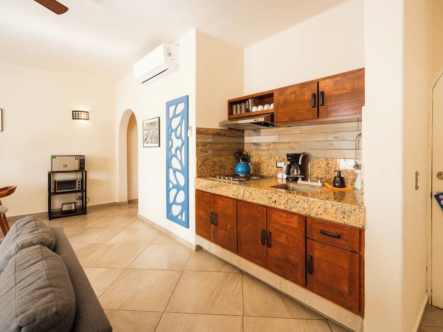 A compact kitchen with wooden cabinets, a granite countertop, and a coffee maker.