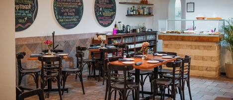 A restaurant interior with tables, chairs, chalkboard menus, and a bar area.