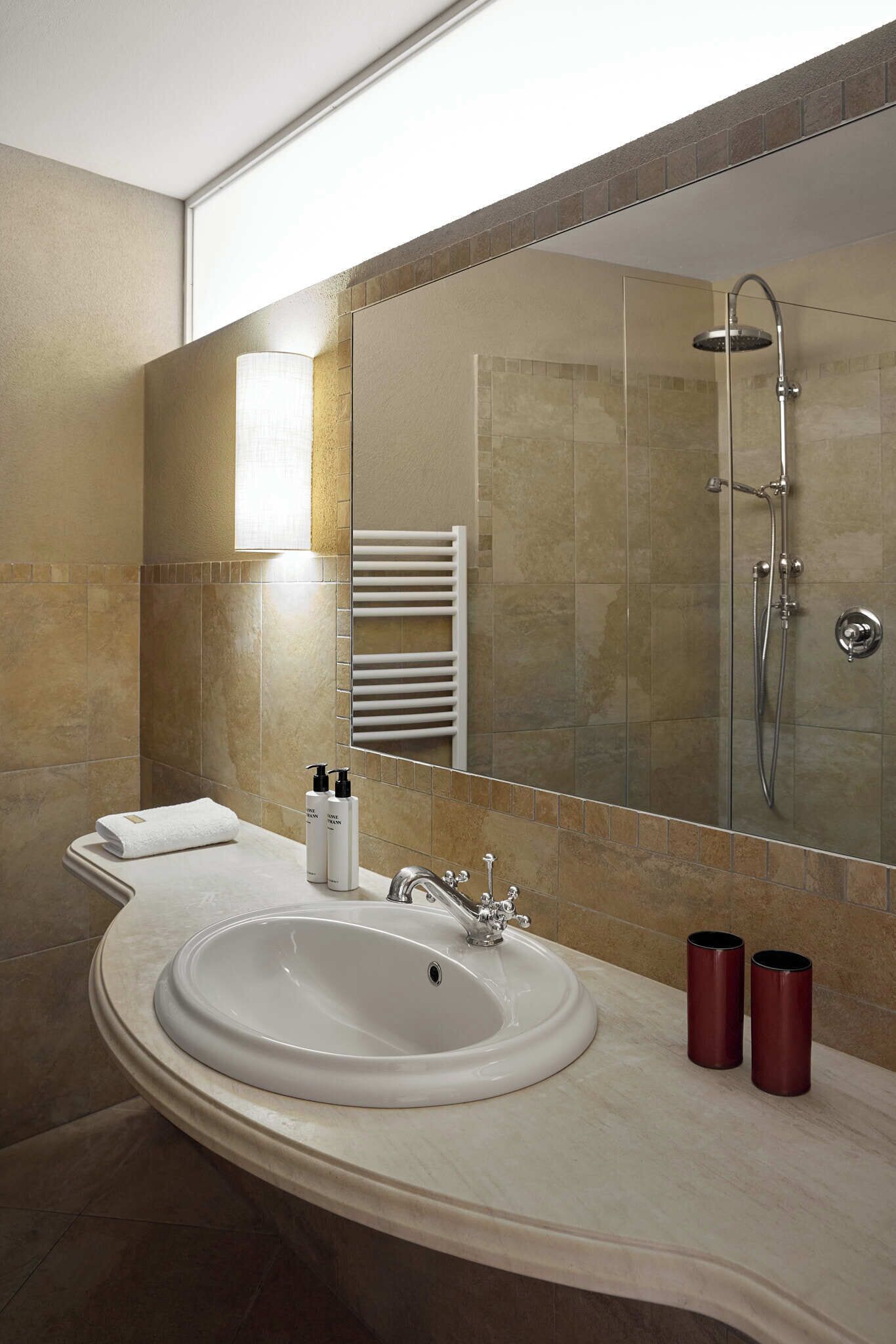 A modern bathroom with a large sink, a glass shower enclosure, and a towel rack.