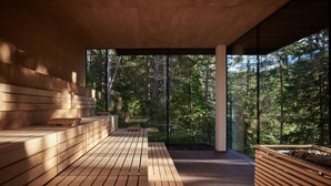 Un área de spa moderna con bancos de madera y una pared de vidrio que ofrece vistas a un bosque.