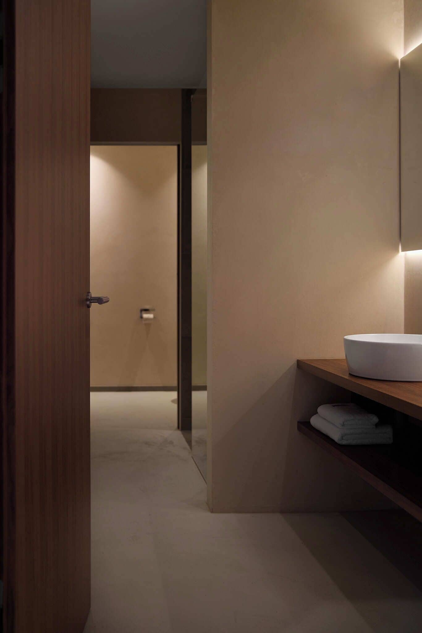 Une salle de bain moderne avec une porte en bois, un lavabo blanc et un miroir.