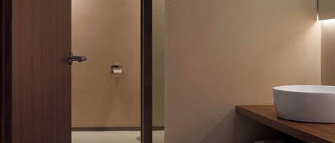 Une salle de bain moderne avec une porte en bois, un lavabo blanc et un miroir.