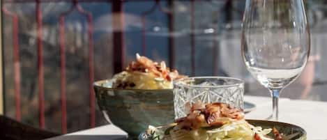 A table with two bowls of food and a wine glass, set against a scenic mountain backdrop.