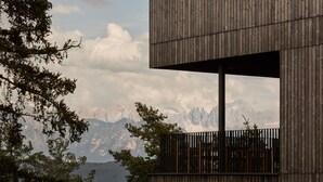 Un edificio moderno con un balcón que da a un paisaje montañoso.
