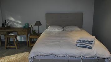 A bedroom with a bed, a desk, and a chair.