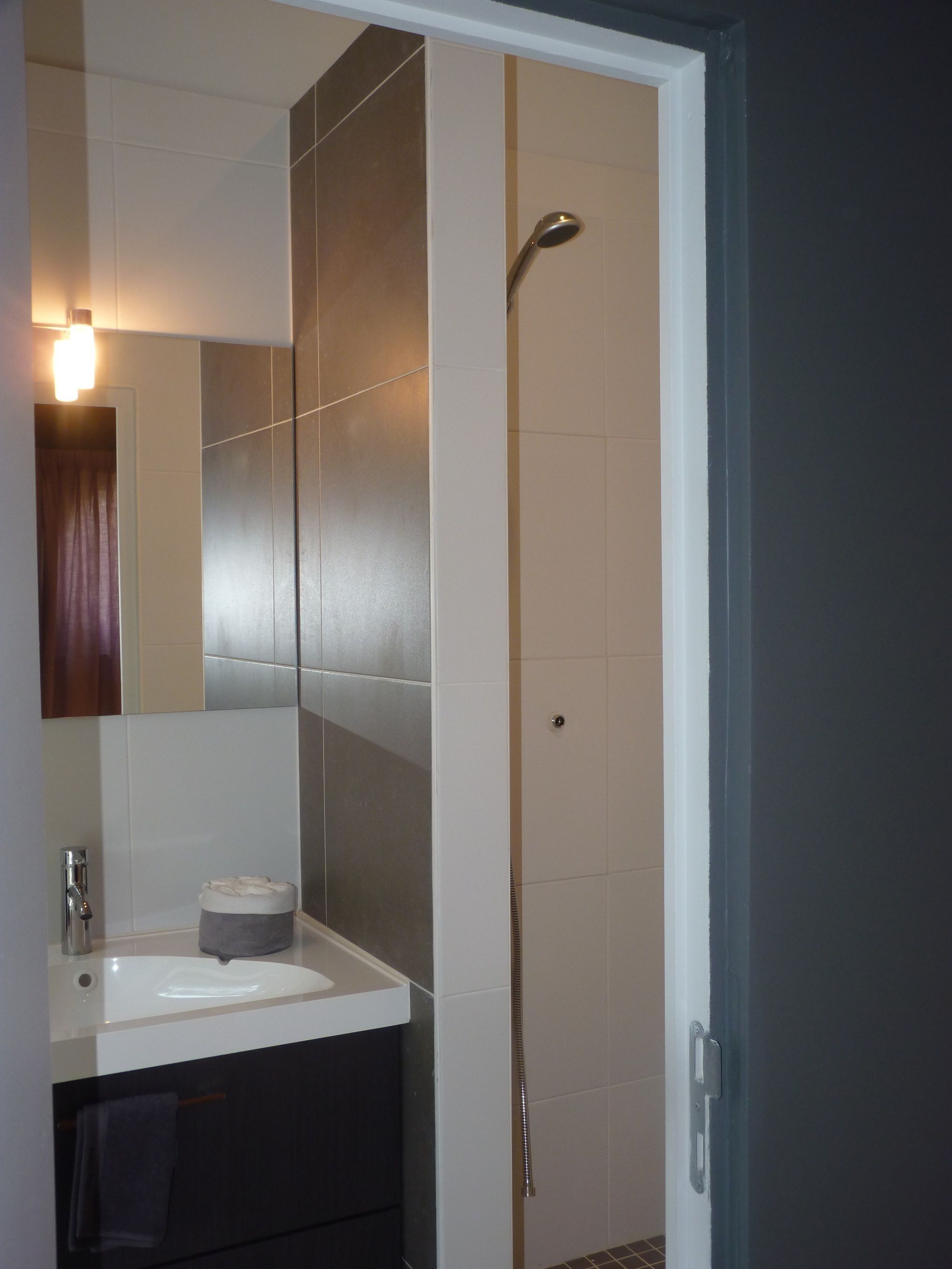 Un baño moderno con un lavabo blanco, un espejo y una ducha.