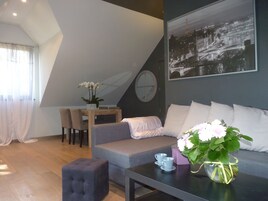 Una sala de estar moderna con un sofá, una mesa de comedor con sillas, una mesa de centro y un jarrón con flores.