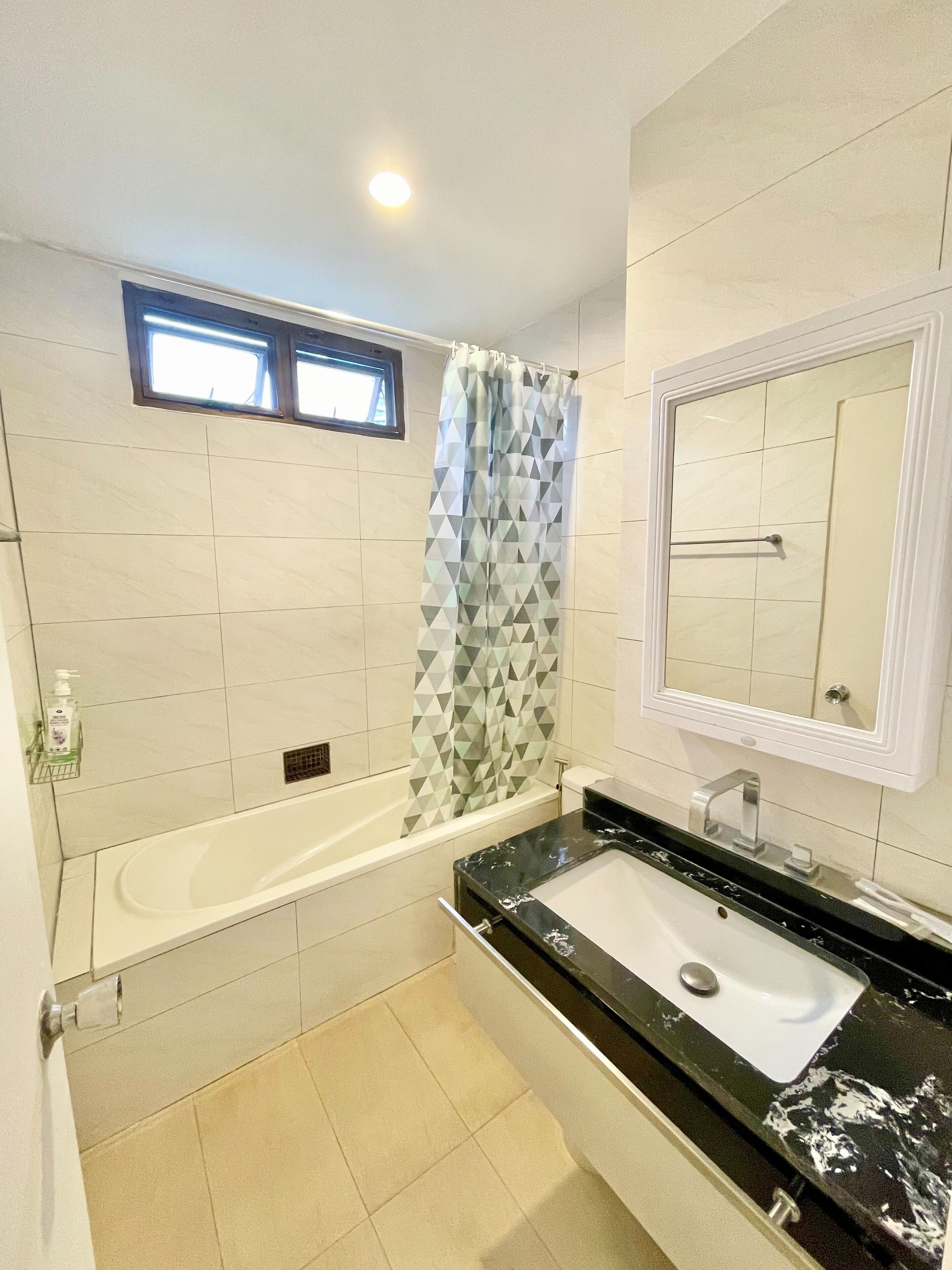 A bathroom with a bathtub, a sink, a mirror, and a shower curtain.