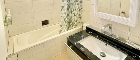 Une salle de bain avec une baignoire, un lavabo, un miroir et un rideau de douche.