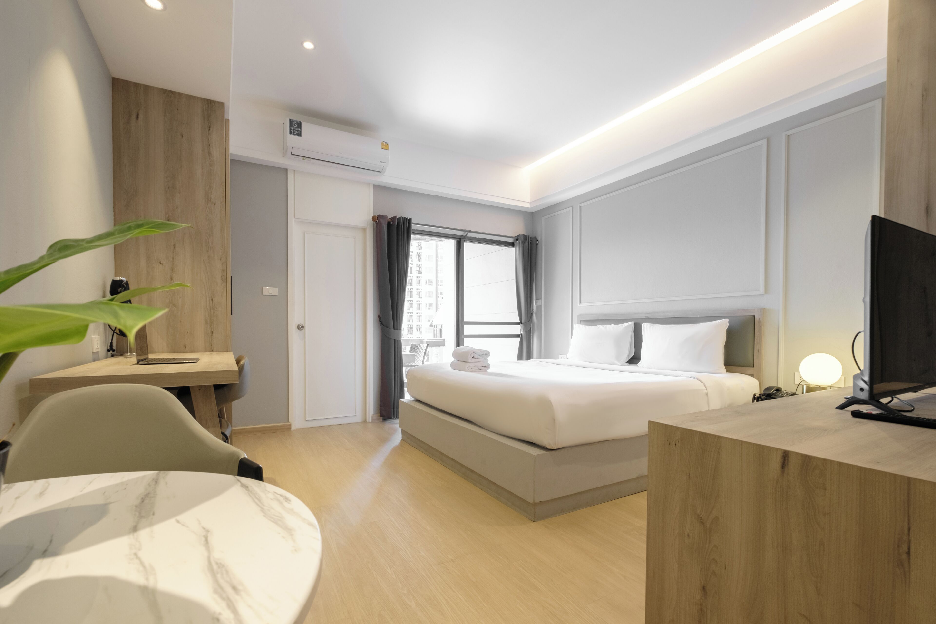 A modern hotel room with a bed, desk, chair, and a TV.