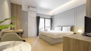 A modern hotel room with a bed, desk, chair, and a TV.
