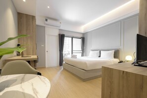 Une chambre d’hôtel moderne équipée d’un lit, d’un bureau, d’une chaise et d’un téléviseur.