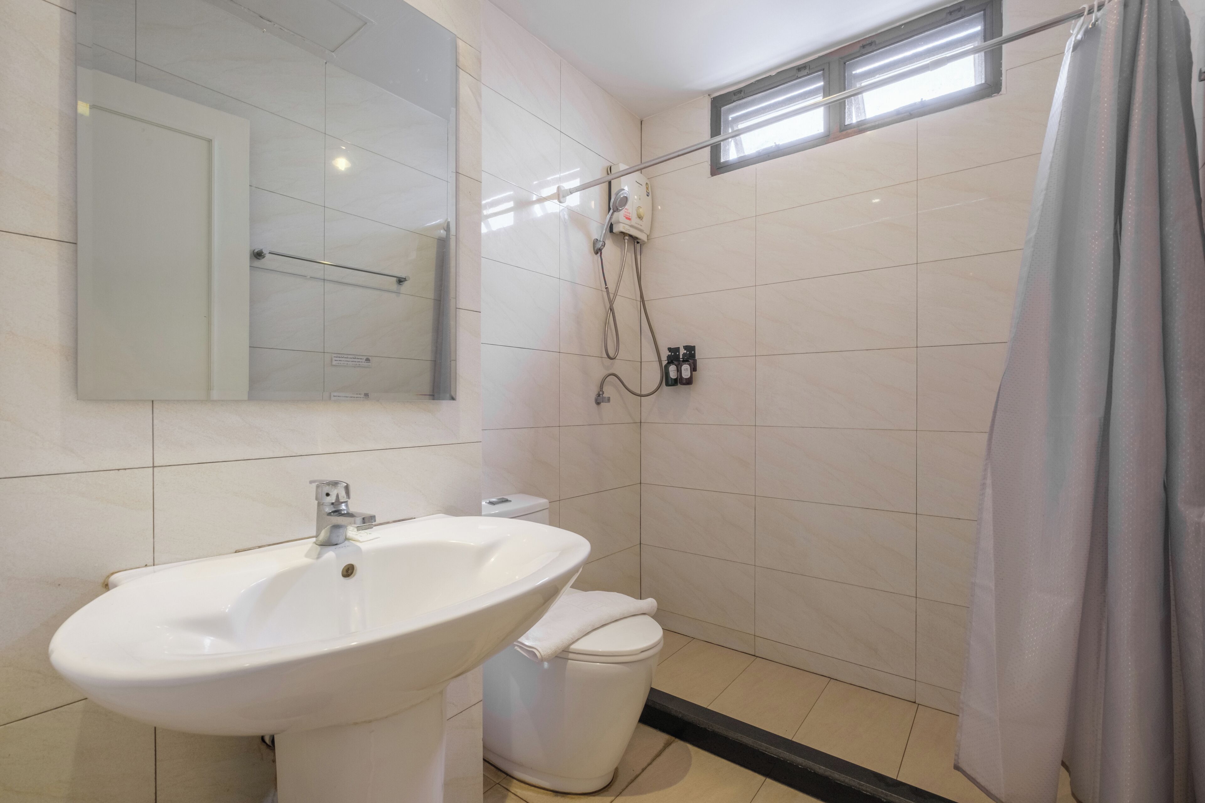 Un baño con lavamanos blanco, inodoro y zona de ducha.