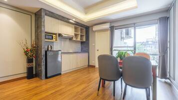 A modern kitchen with built-in appliances, a dining area with two chairs, and a large window offering a city view.