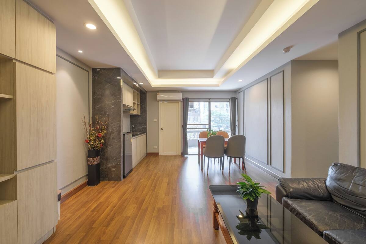 Una cocina moderna con armarios de madera, encimera de mármol y zona de comedor con sofá y sillas.