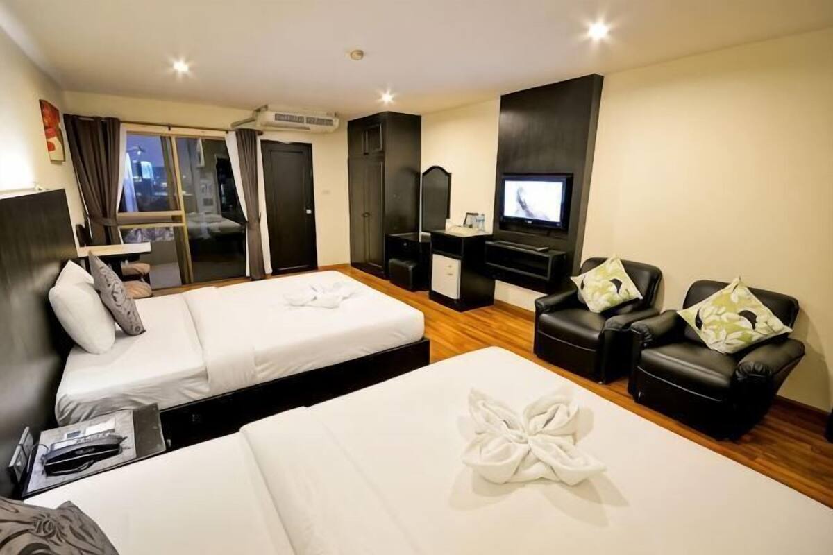 Habitación de hotel con dos camas, televisión, sofá y escritorio.