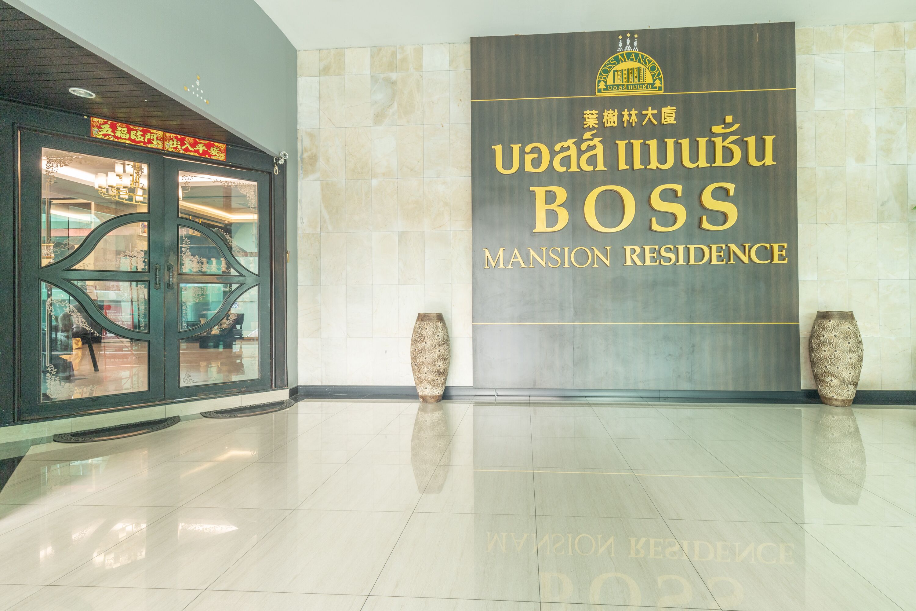 A clean, modern lobby with a sign for 'Mansion Residence' and two decorative vases.