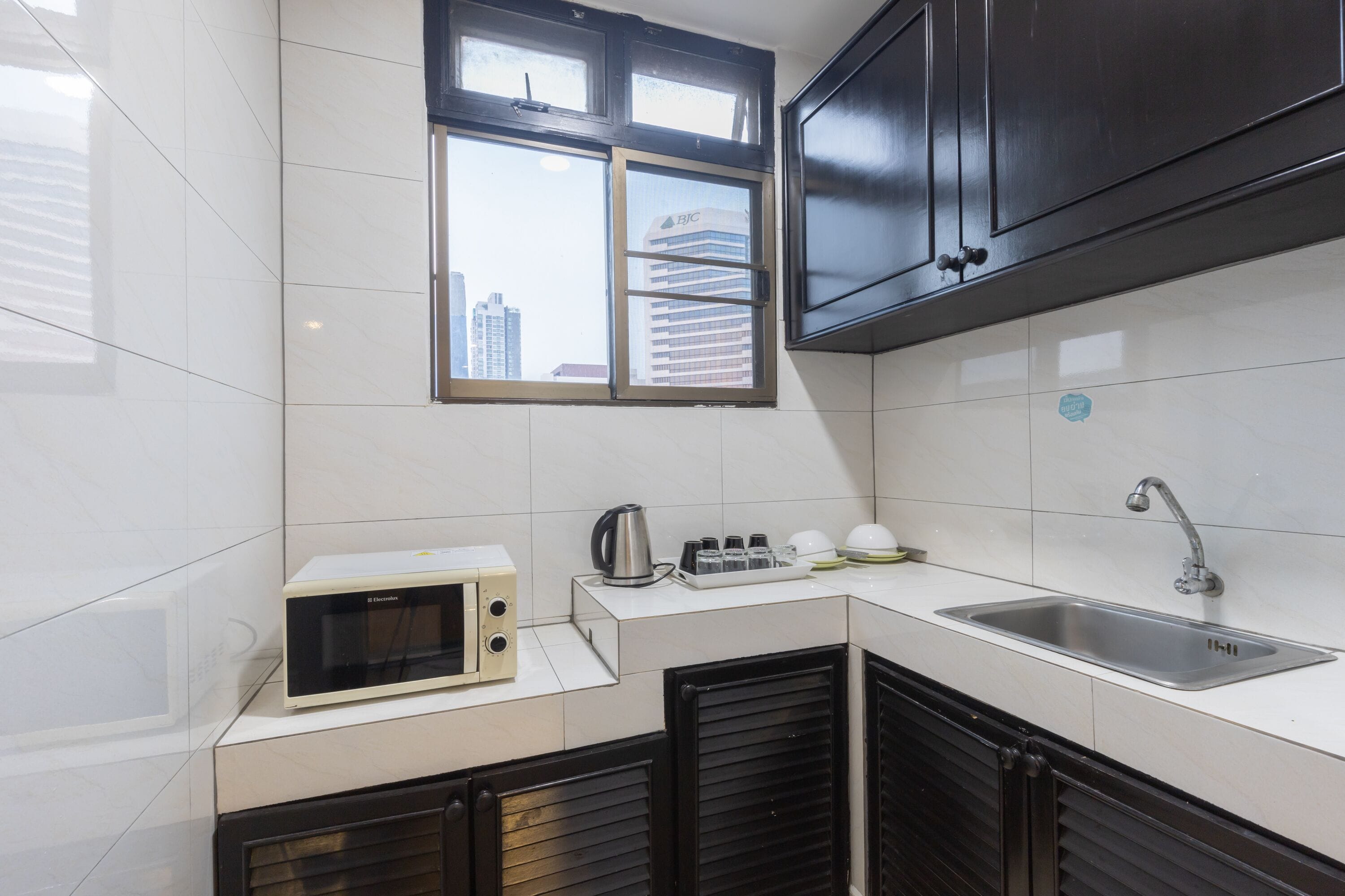 A compact kitchen with a microwave, kettle, and sink.