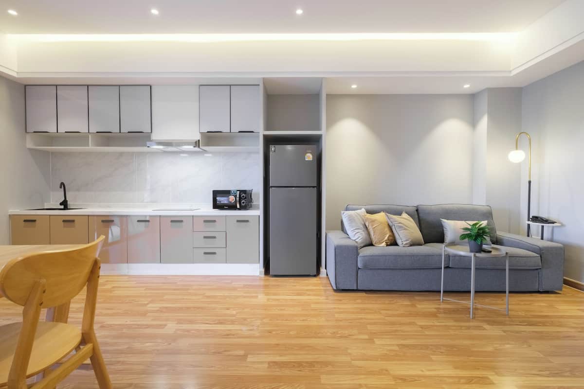 Una cocina moderna con gabinetes grises, un refrigerador gris, y un comedor con una mesa y sillas de madera.