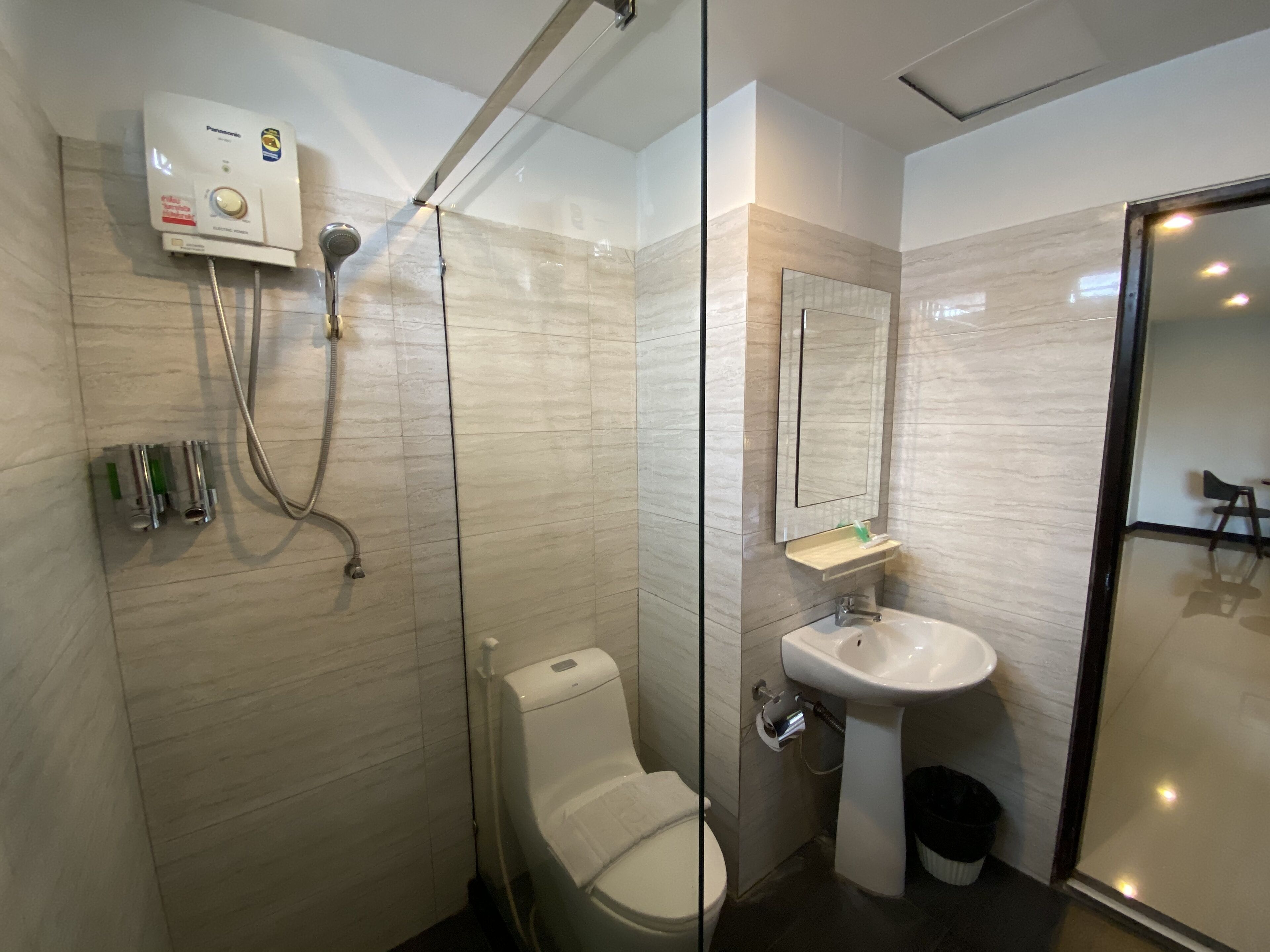 Une salle de bain moderne dotée d’une douche à parois de verre, de toilettes, d’un lavabo et d’un miroir.