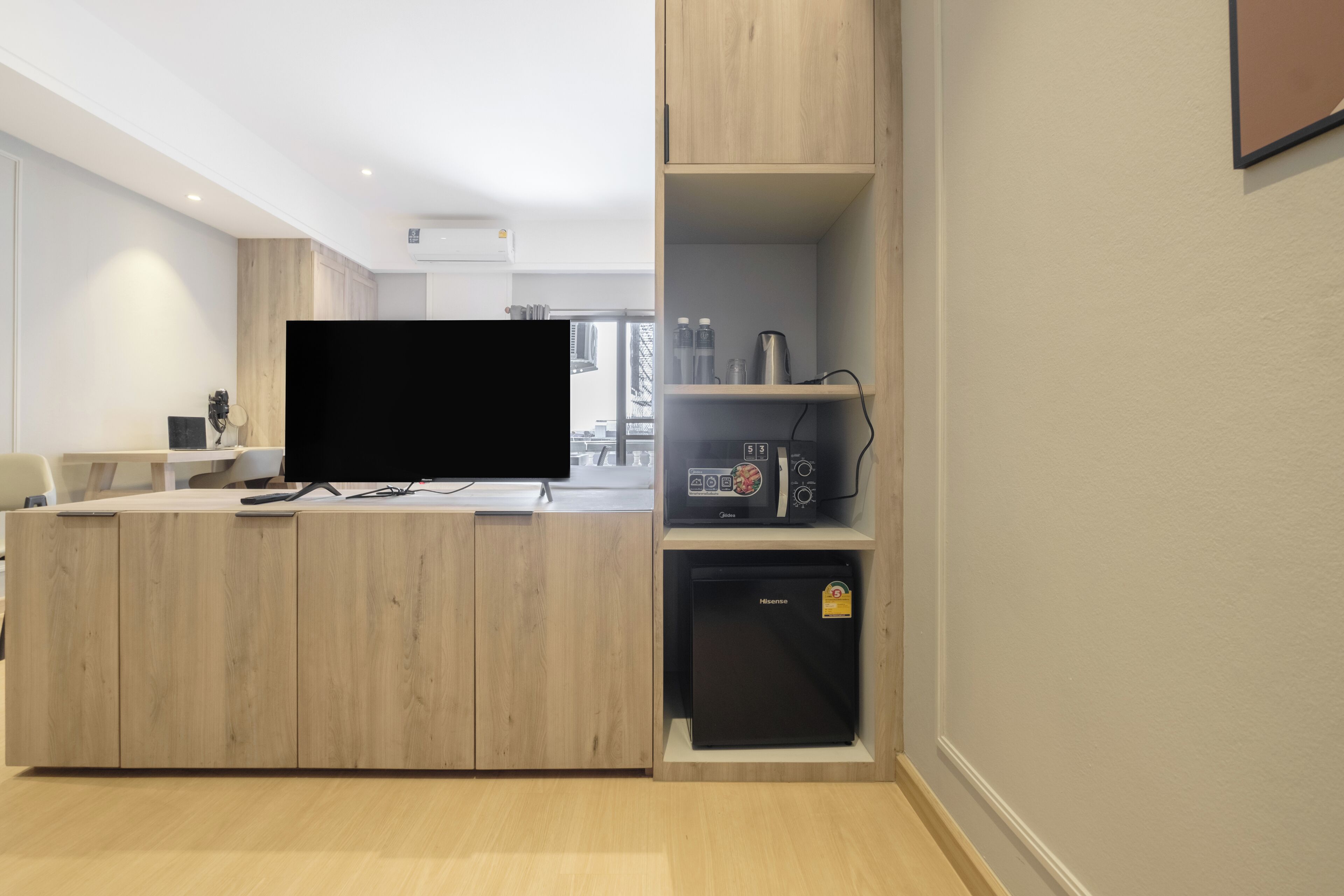A modern kitchen with a built-in microwave, a refrigerator, and a flat-screen TV on a wooden counter.