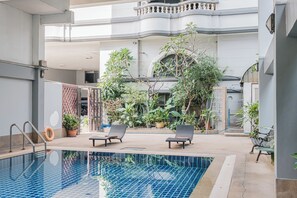 Une piscine intérieure dotée de chaises longues et de plantes en pot.