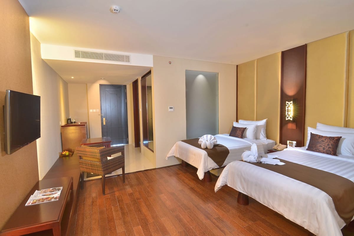 Een hotelkamer met twee bedden, een televisie, een bureau en een stoel.