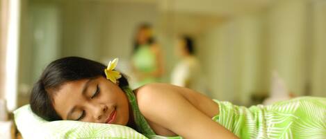 A person lying on a bed with a green patterned blanket and pillow.