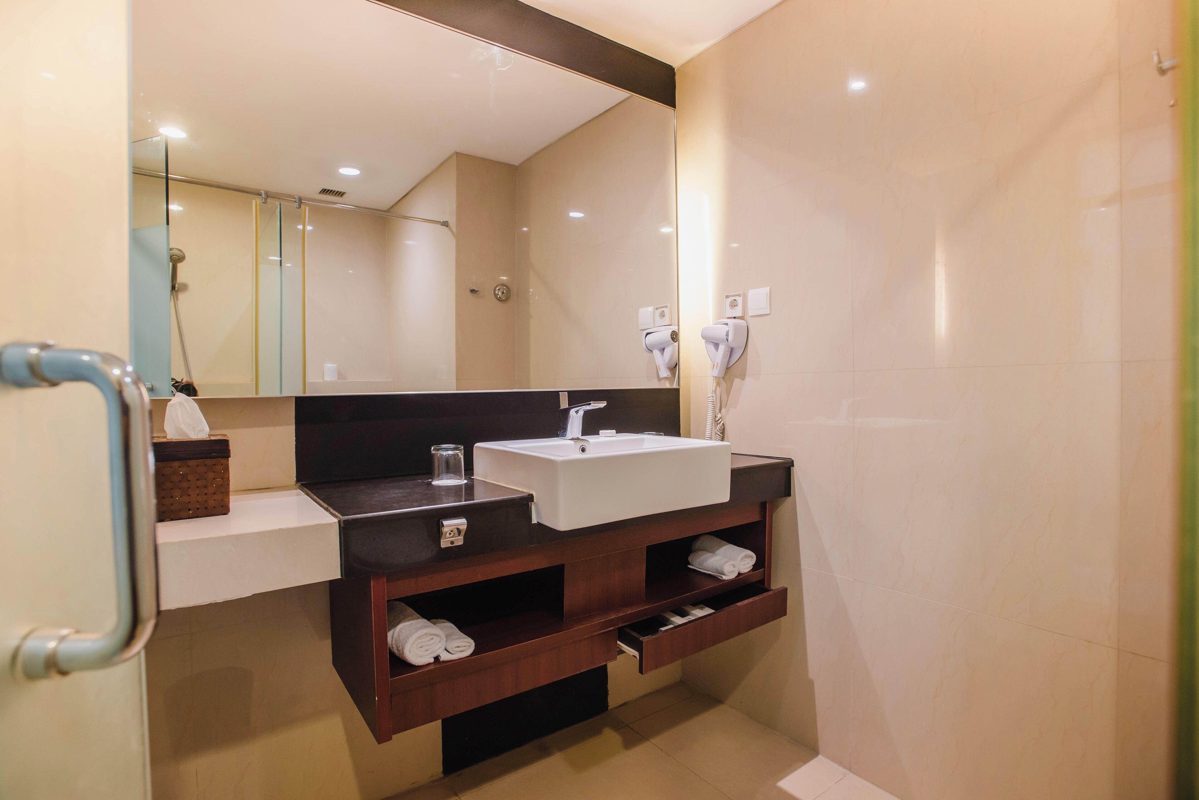 Un baño moderno con un espejo grande, un lavabo blanco, un perchero para toallas y un estante para toallas.