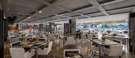 A spacious restaurant with high ceilings and natural light. Tables are arranged in a casual layout, and the floor is wooden.