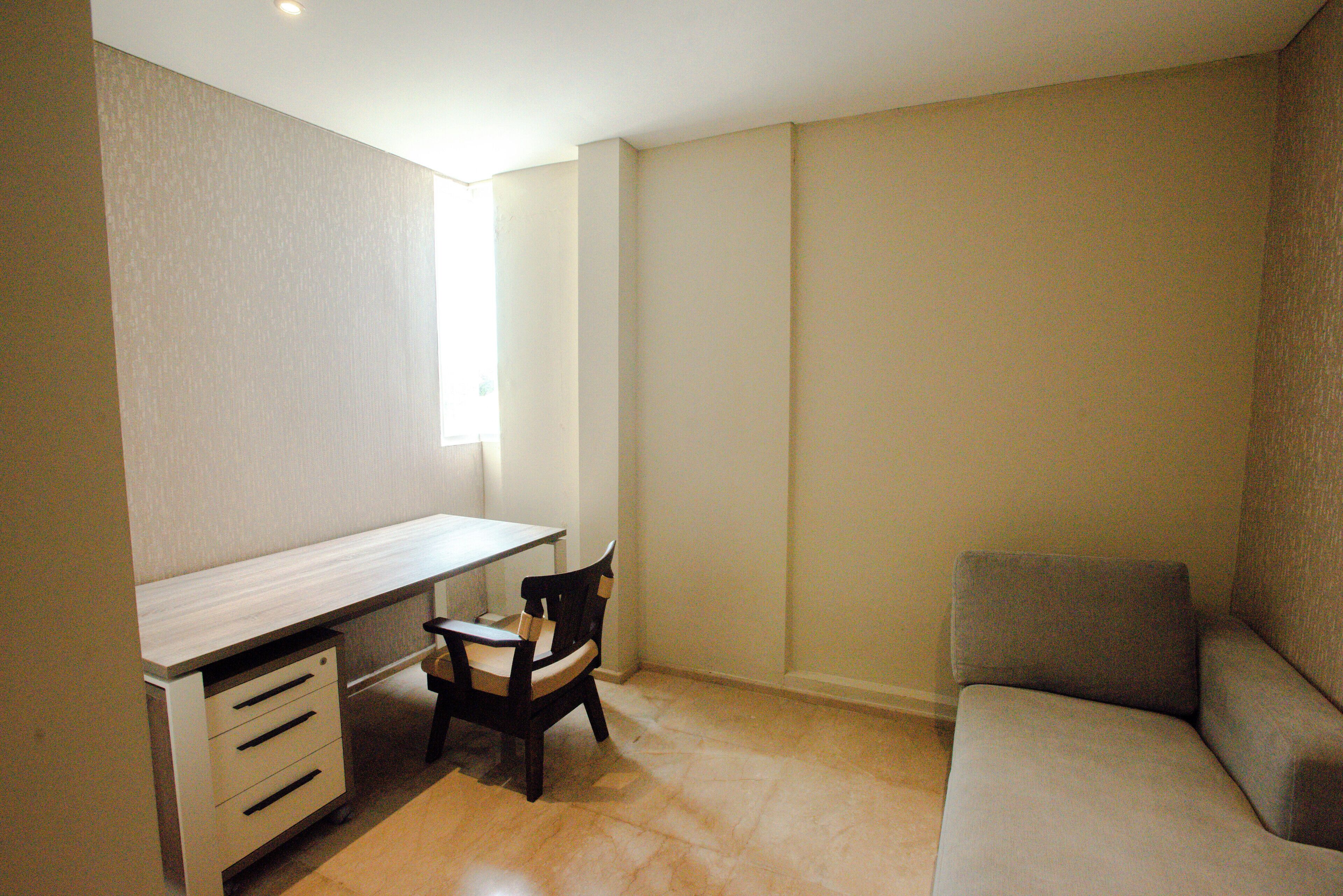 A room with a desk, a chair, a sofa, and a window.