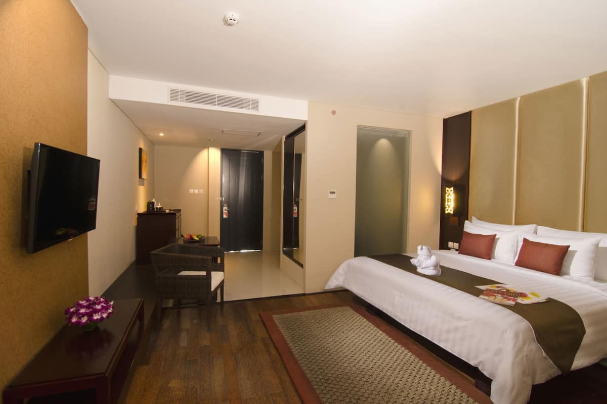 Een hotelkamer met een bed, een televisie, een bureau en een stoel.