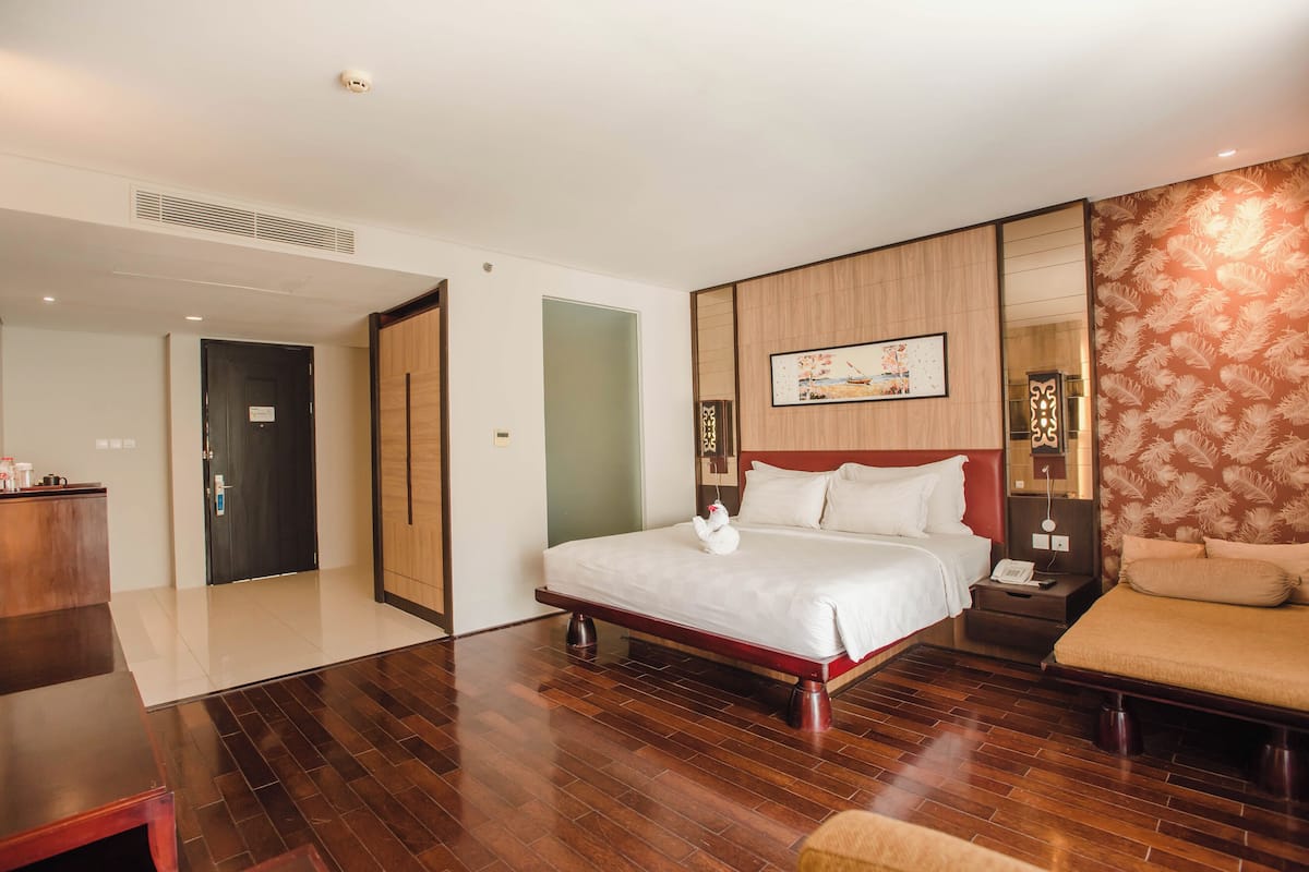 Een hotelkamer met een groot bed, een nachtkastje, een stoel, een bureau en een spiegel.