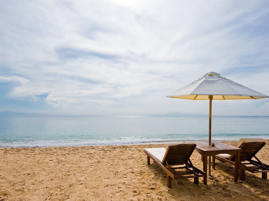 Una playa cerca, arena blanca, sombrillas, toallas de playa