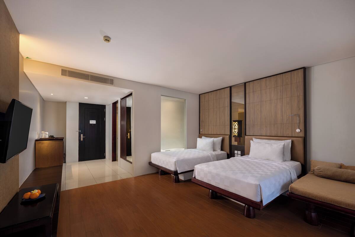 Een hotelkamer met twee bedden, een bank, een televisie en een bureau.