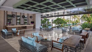 Un vestíbulo amplio con techo alto, mobiliario moderno y vistas al área de la piscina exterior.