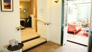 A hotel lobby with a staircase leading to a second floor, a reception desk, and a glimpse of a dining area with outdoor seating. - Marguerite d'Anjou (Angers)