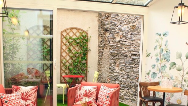 A cozy indoor seating area with a red sofa, a round table, and a chair. - Marguerite d'Anjou (Angers)