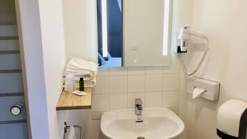 Un baño con lavamanos, espejo, toallero, secamanos y teléfono.