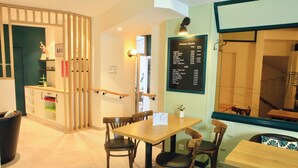 A restaurant interior with a wooden table and chairs, a menu board, and a counter with a cash register. - Marguerite d'Anjou (Angers)