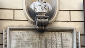 Busto de mármore com inscrições numa fachada de edifício.