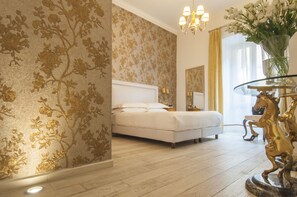 A bedroom with a bed, a chandelier, a vase with flowers, and a golden horse statue. - Ripetta Rooms (Rome)