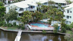 A resort with a swimming pool surrounded by palm trees and a dock. - Surfers Del Rey (Surfers Paradise)