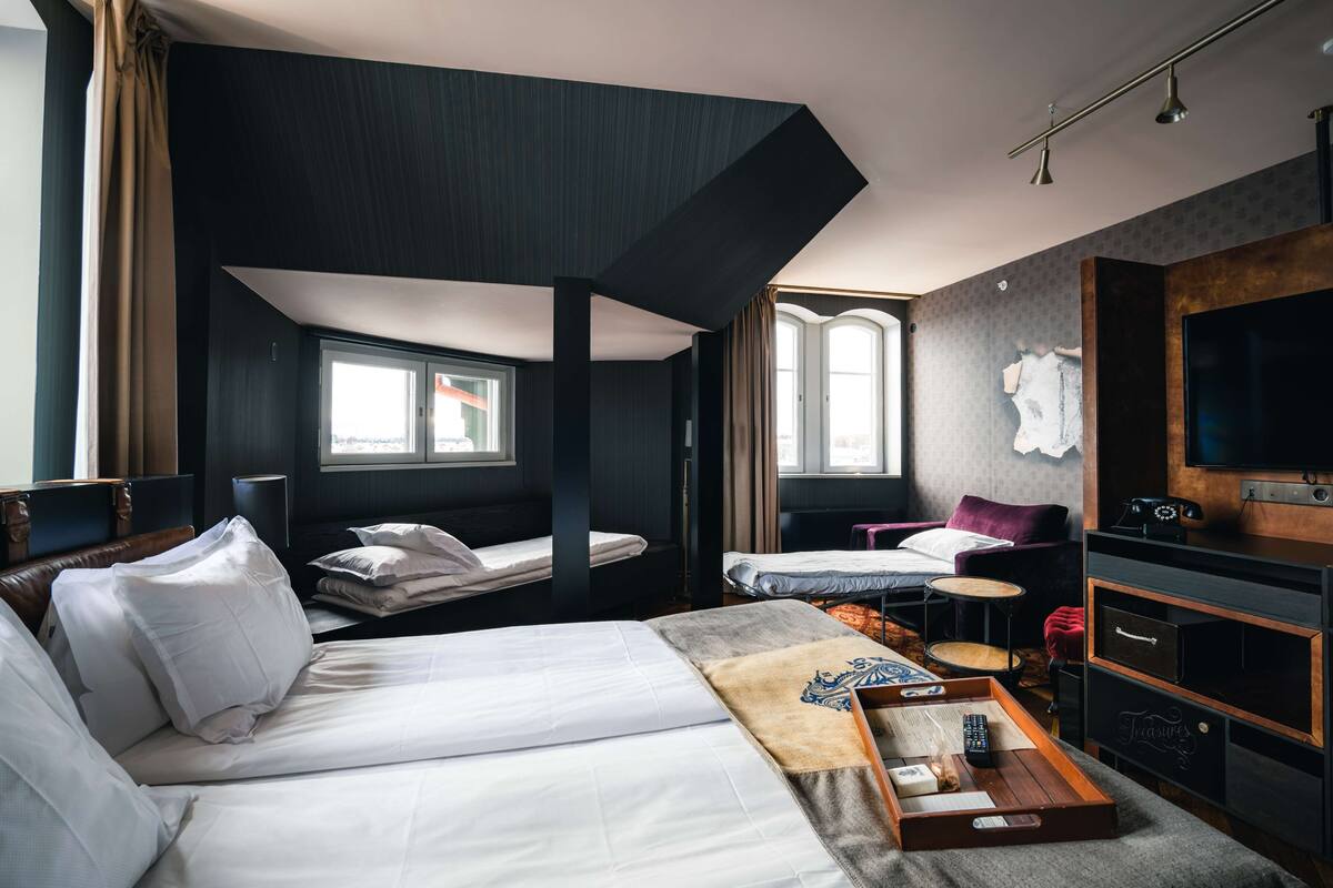 A hotel room with a large bed, a desk, a chair, a TV, and a window.