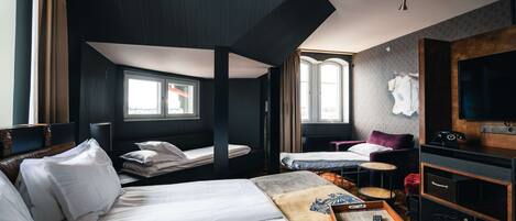A hotel room with a large bed, a desk, a chair, a TV, and a window.