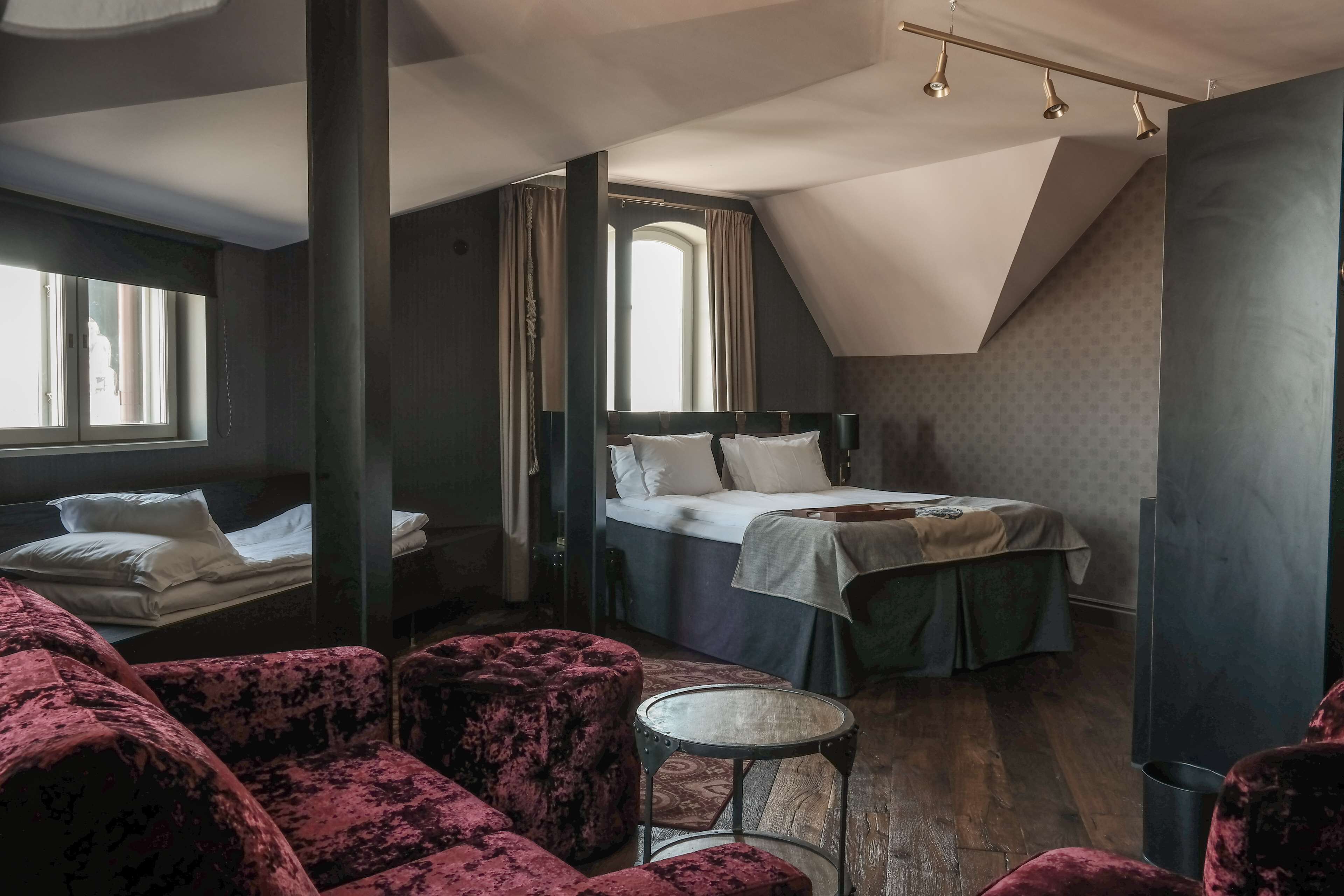 A bedroom with a bunk bed, a small round table, and a red velvet chair.