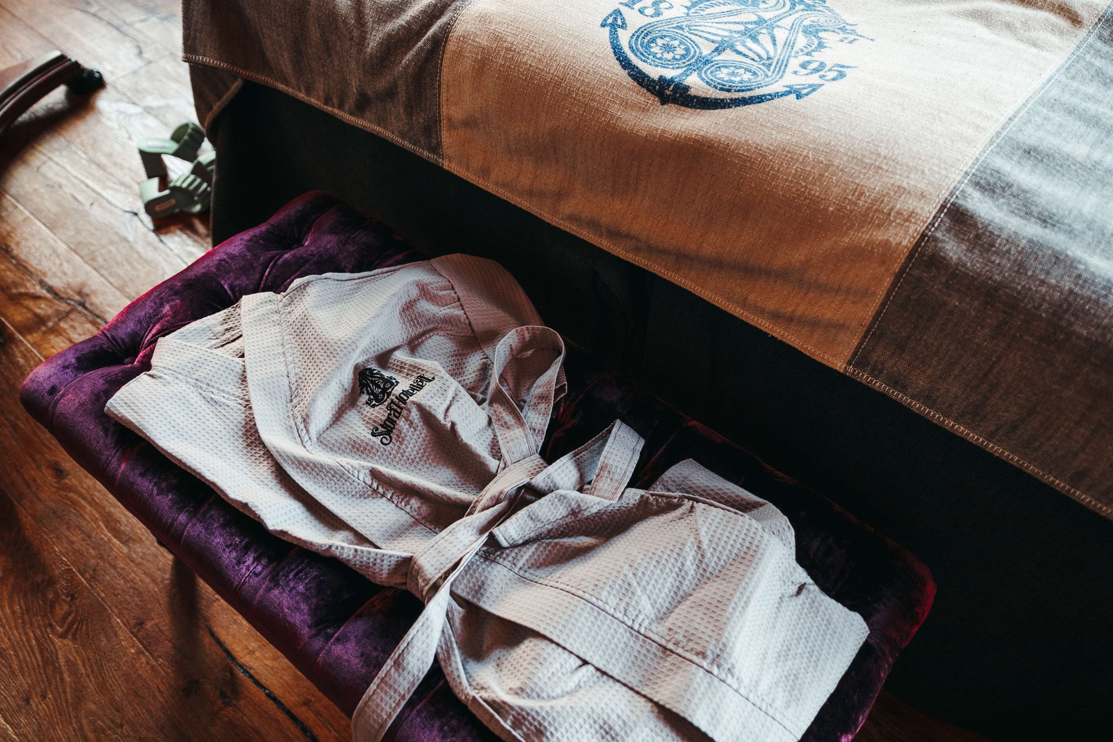 A bed with a brown headboard and a white pillow with a blue design.